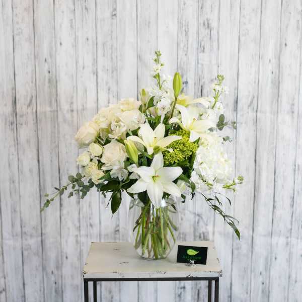 White floral arrangement in a clear glass vase on a small table