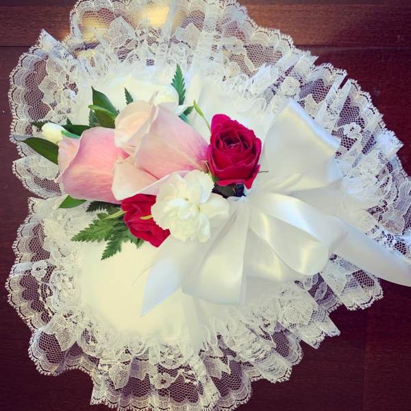 Pink and white roses arranged with lace and a white ribbon