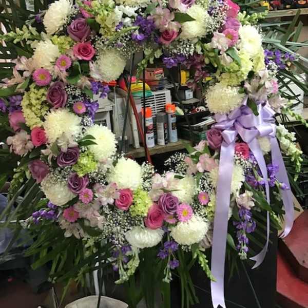 Large floral wreath with pink, purple, and white flowers and a lavender ribbon
