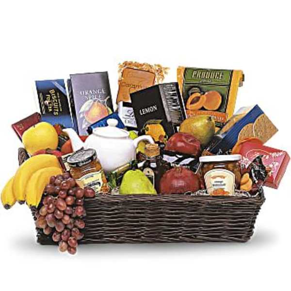 Gift basket with fruit, snacks, and a white teapot