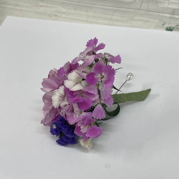 Small corsage with pink and white flowers and a green ribbon
