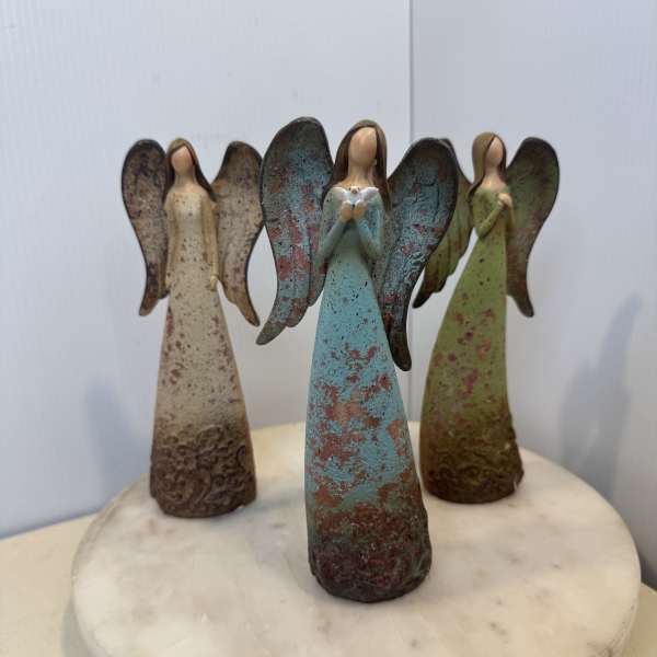 Three angel figurines standing on a round marble base