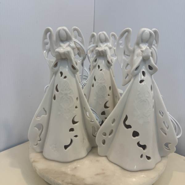 Three white ceramic angel figurines on a round base