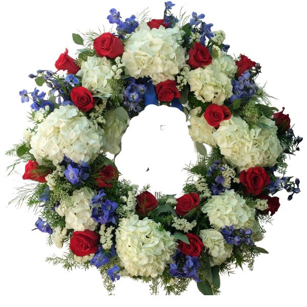 Circular floral wreath with red roses, white hydrangeas, and blue flowers
