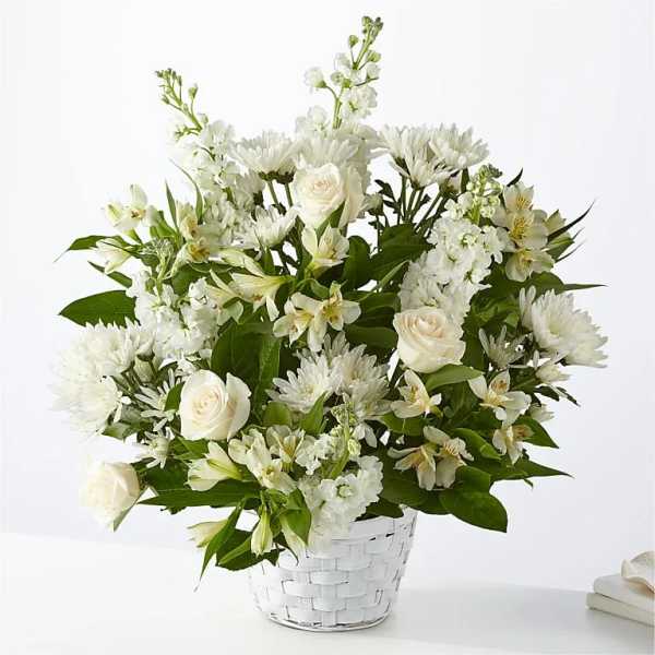White roses and mixed white flowers in a white basket vase