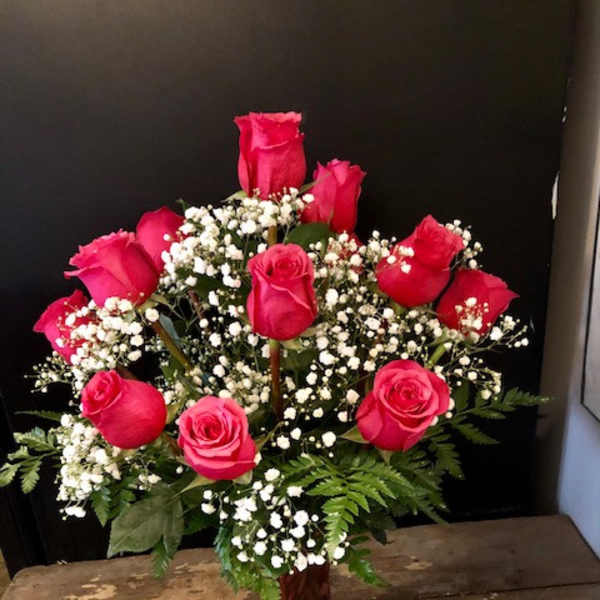 Pink roses arranged with baby's breath in a red vase