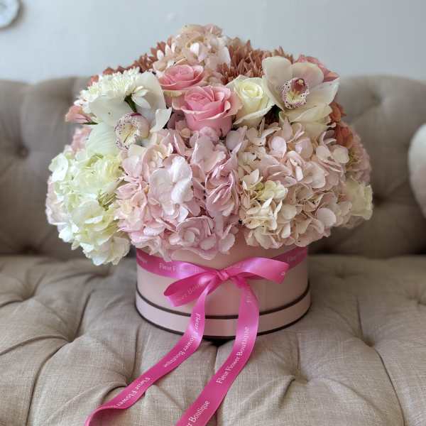 Round pastel bouquet in a pink hat box with a ribbon bow