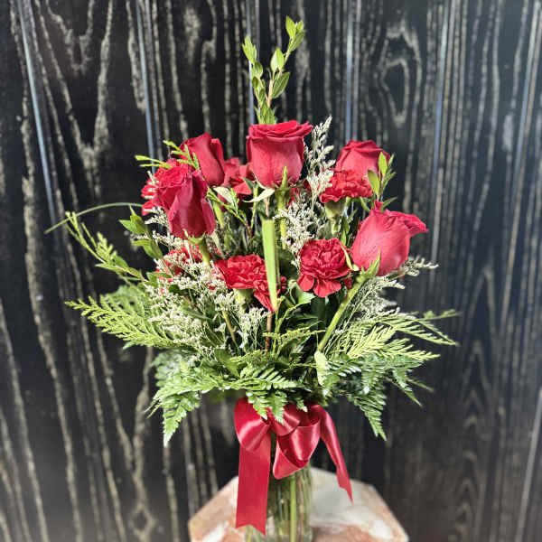 Red roses and carnations in a glass vase with a red ribbon
