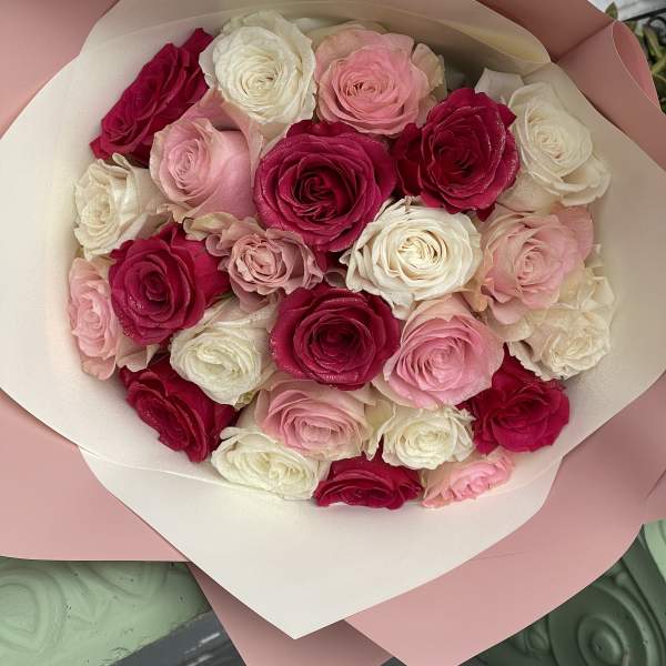Bouquet of pink, white, and red roses wrapped in blush paper