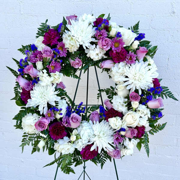 Circular floral wreath with white, pink, and purple flowers on a stand