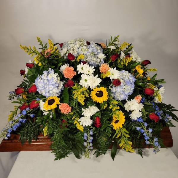 Large casket spray with mixed flowers in red, white, yellow, and blue
