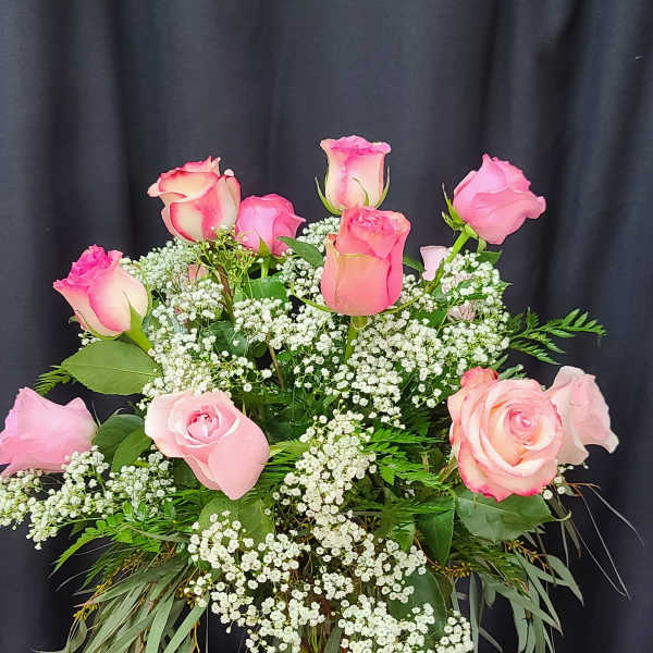 Pink roses in a clear glass vase with white filler flowers