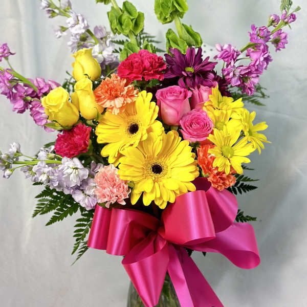 Bright mixed bouquet with yellow gerbera daisies and pink roses, tied with a hot pink ribbon