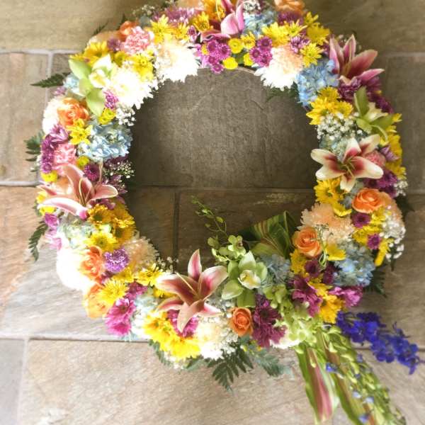 Circular floral wreath with mixed pink, yellow, blue, and orange blooms