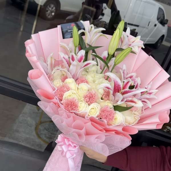 Pink-wrapped bouquet of lilies, roses, and carnations