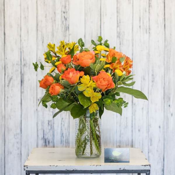 Orange and yellow flowers arranged in a clear glass vase