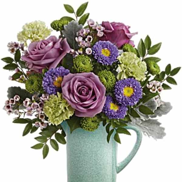 Purple roses and mixed blooms in a mint ceramic pitcher