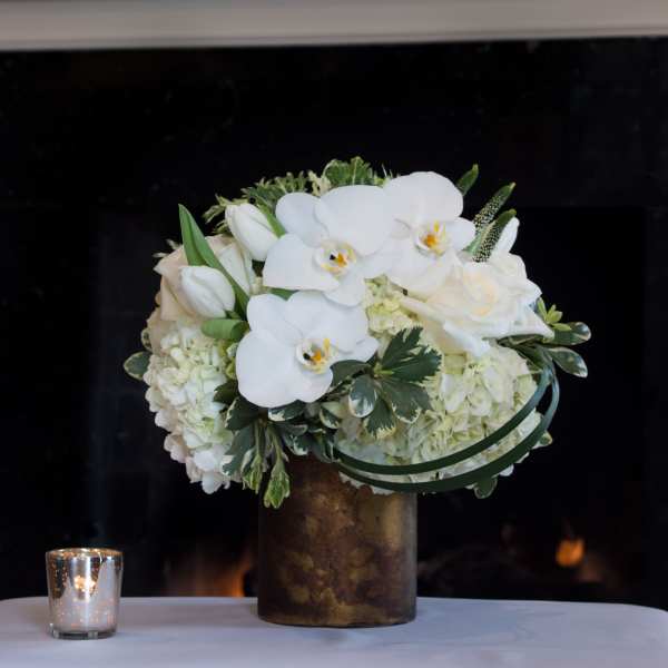 White orchid and rose arrangement in a bronze vase