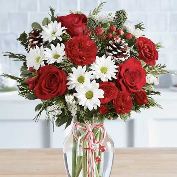 Red roses and white daisies in a glass vase with a ribbon