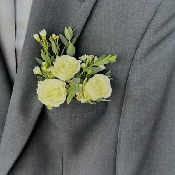 White floral boutonniere pinned to a gray suit jacket
