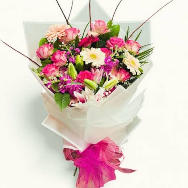 Bouquet of pink roses, white daisies, and lilies wrapped in white paper