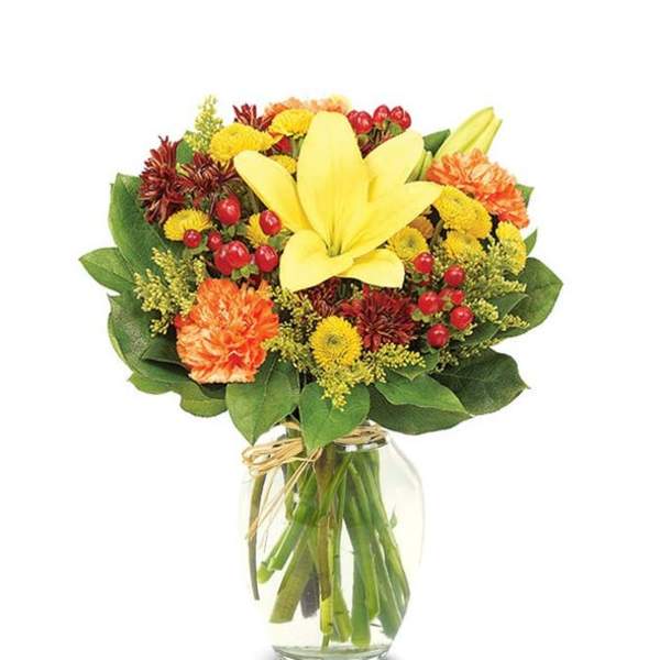 Yellow lily bouquet with orange and red flowers in a glass vase