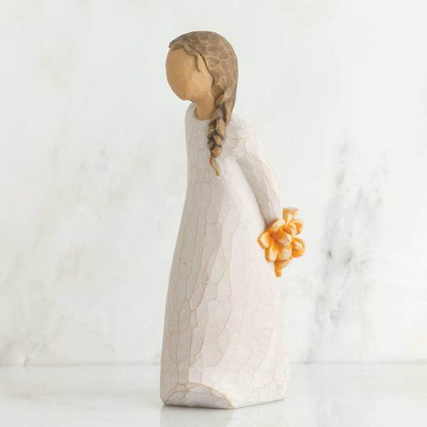 Small figurine of a girl in a white dress holding orange flowers