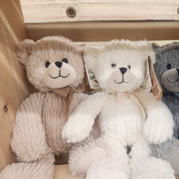 Three plush teddy bears in a wooden crate