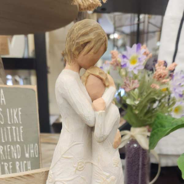 Decorative figurine of two people embracing, with a small flower arrangement behind it