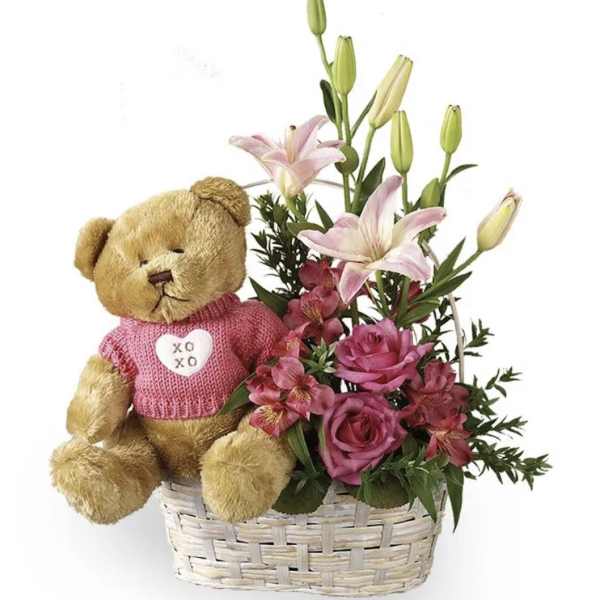 Teddy bear in a basket with pink flowers and lilies