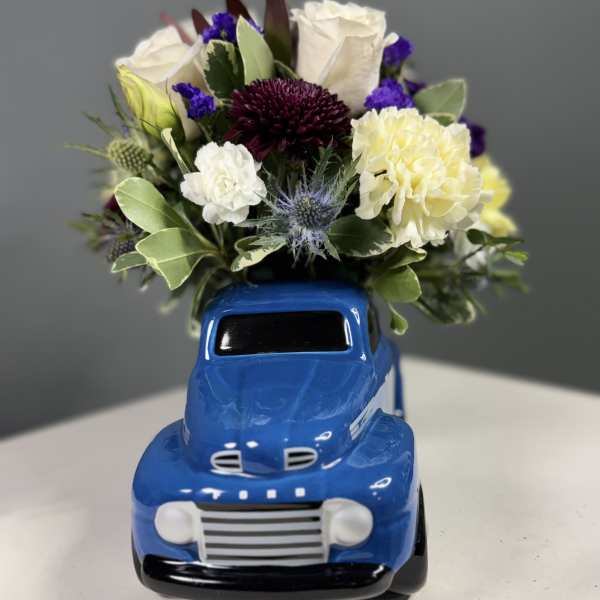 Bouquet of mixed flowers arranged in a blue truck-shaped vase