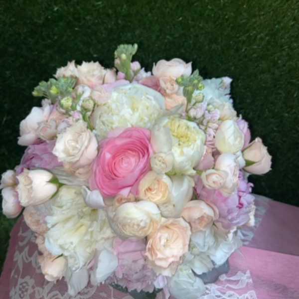 Round bouquet of pale pink and white flowers with a bright pink center bloom