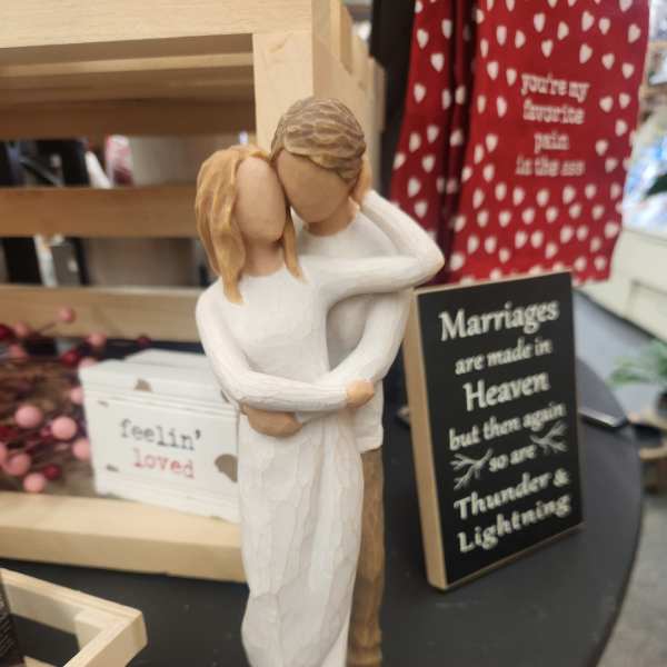 Wooden figurine of a couple embracing beside wedding-themed signs