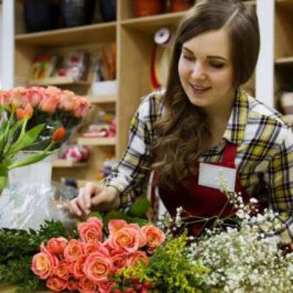 Florist arranging pink roses and mixed flowers at a worktable