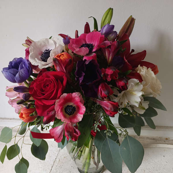Mixed bouquet of red, pink, purple, and white flowers in a glass vase