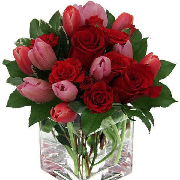Red roses and pink tulips arranged in a clear square vase