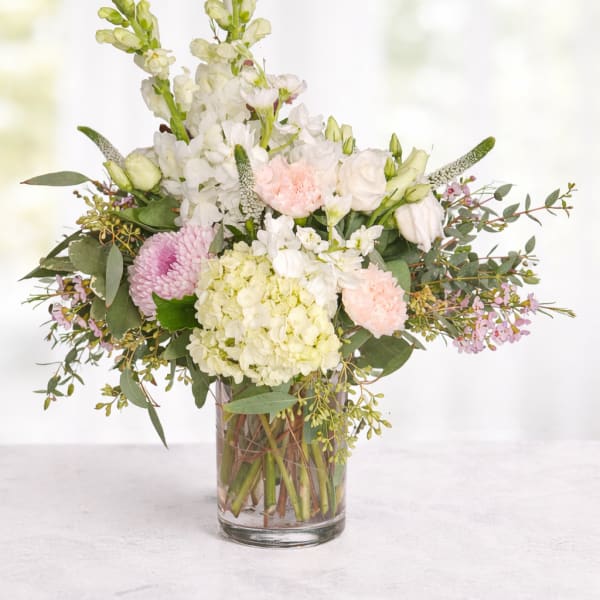 Pastel flower arrangement in a clear glass vase with white and pink blooms