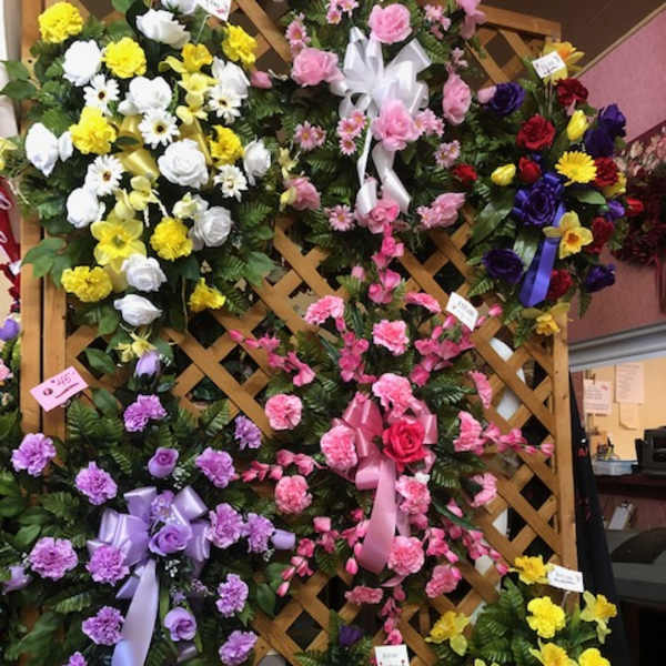 Assorted floral wreaths and sprays on a lattice display