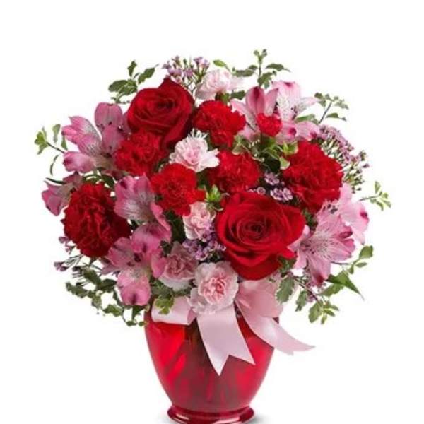 Red and pink flower bouquet in a red vase with a pink ribbon