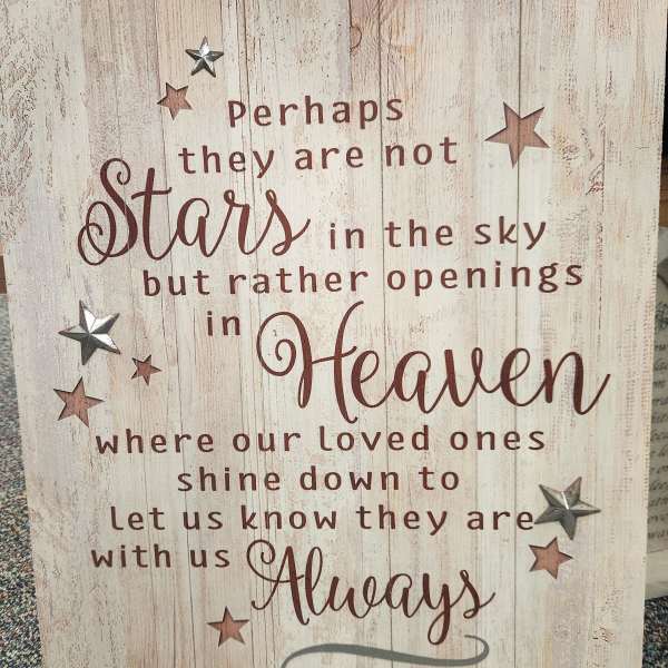 Wooden sign with a memorial quote and star accents