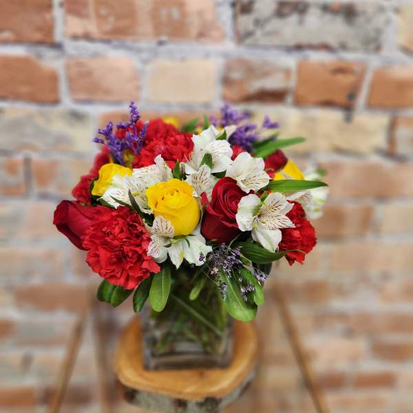 Bouquet of red and yellow roses with white alstroemeria in a glass vase