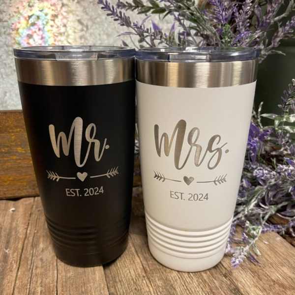 Two engraved tumblers labeled Mr. and Mrs. beside purple flowers.