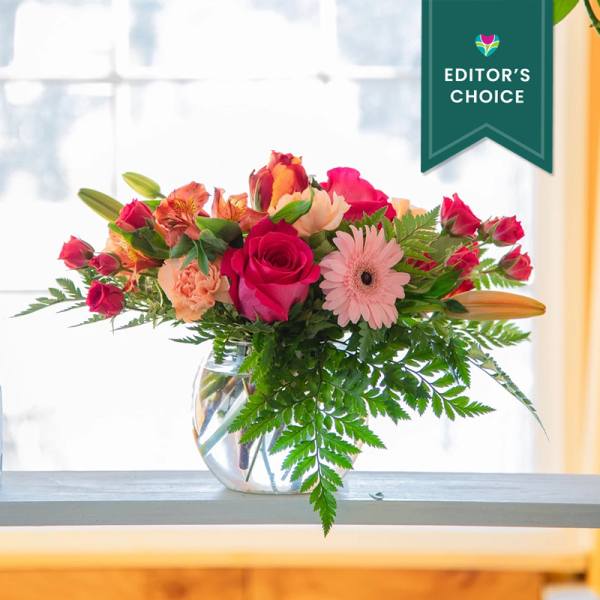 Mixed bouquet of pink and orange flowers in a clear glass vase