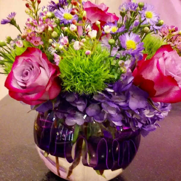 Bouquet of pink roses, purple daisies, and green filler in a round vase