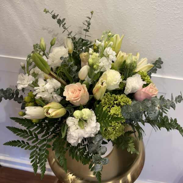 Mixed bouquet of white and pale peach flowers in a gold vase