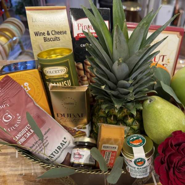 Gift basket with fruit, snacks, and a red rose