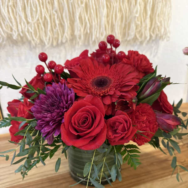 Red and purple flower arrangement in a glass vase