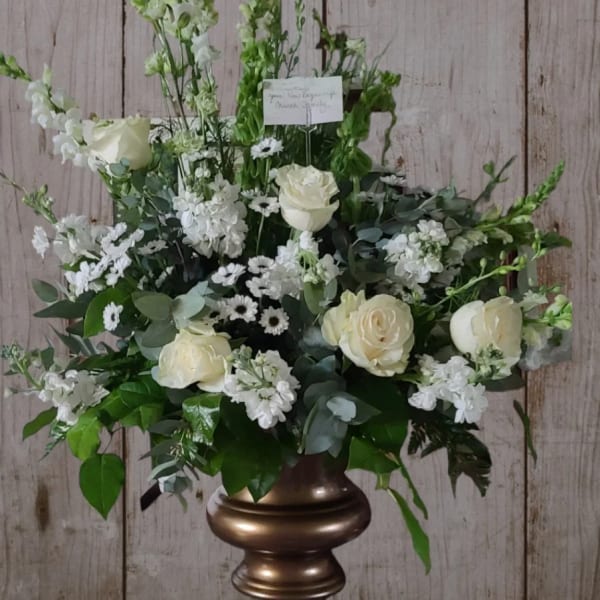 White floral arrangement with roses and tall snapdragons in a bronze vase