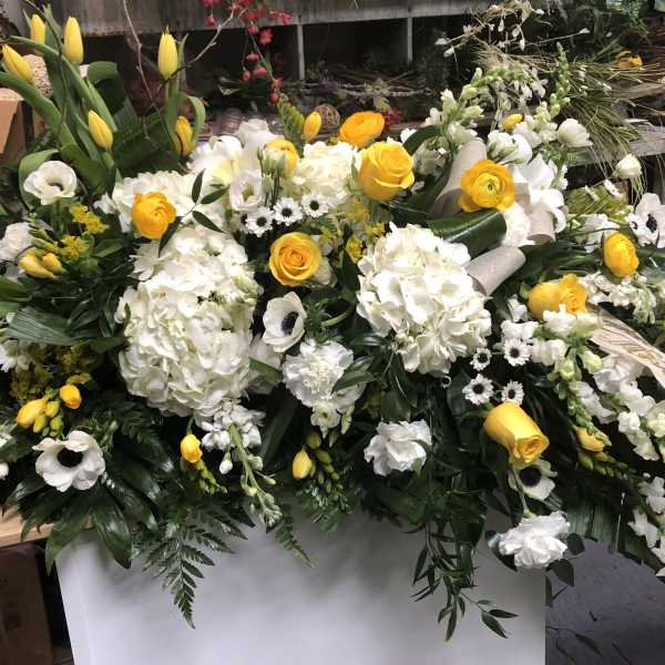 Large white and yellow floral casket spray with ribbon accents