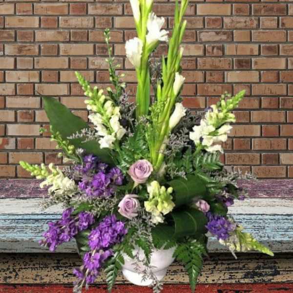 Tall floral arrangement with purple and white blooms in a white vase